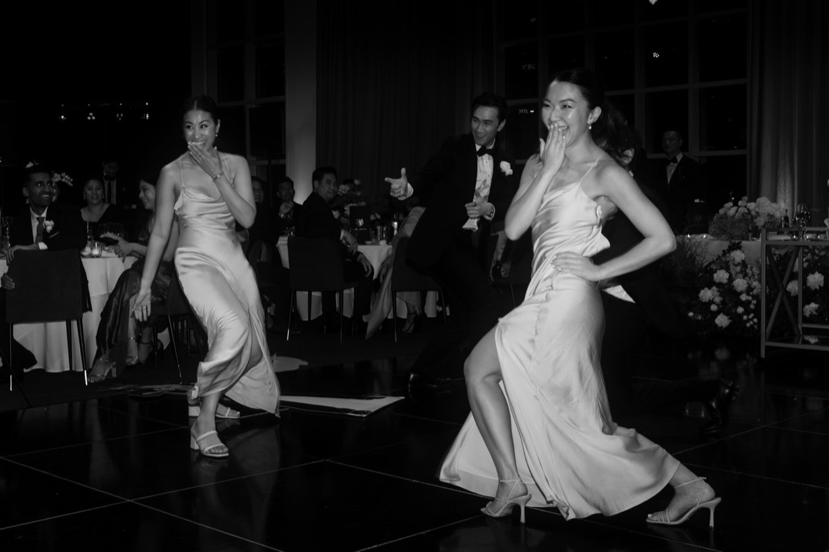 Two women dancing on a dark dance floor, one in a slip dress laughing