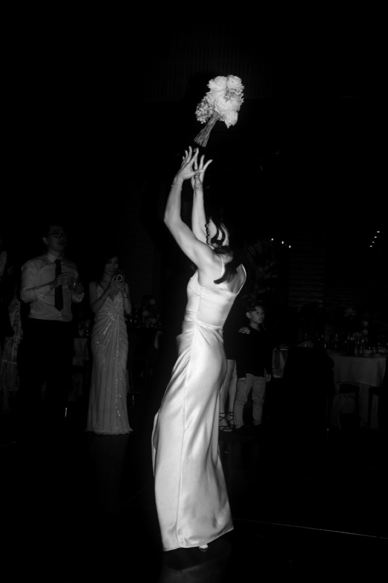 Silhouette of the bride launching her bouquet high into the air at night