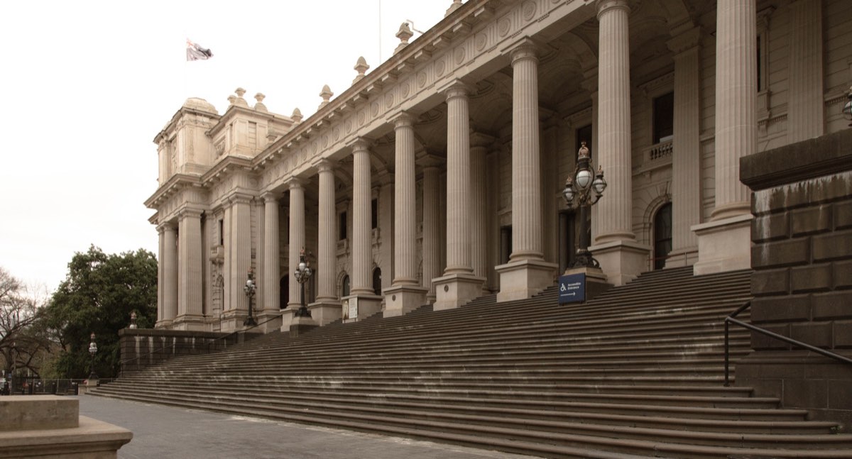 The wide stone steps and colonnade of Parliament House, Melbourne under a grey sky
