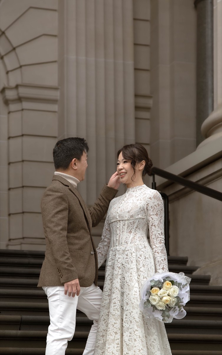 Groom gently touches the bride's cheek on the Parliament steps