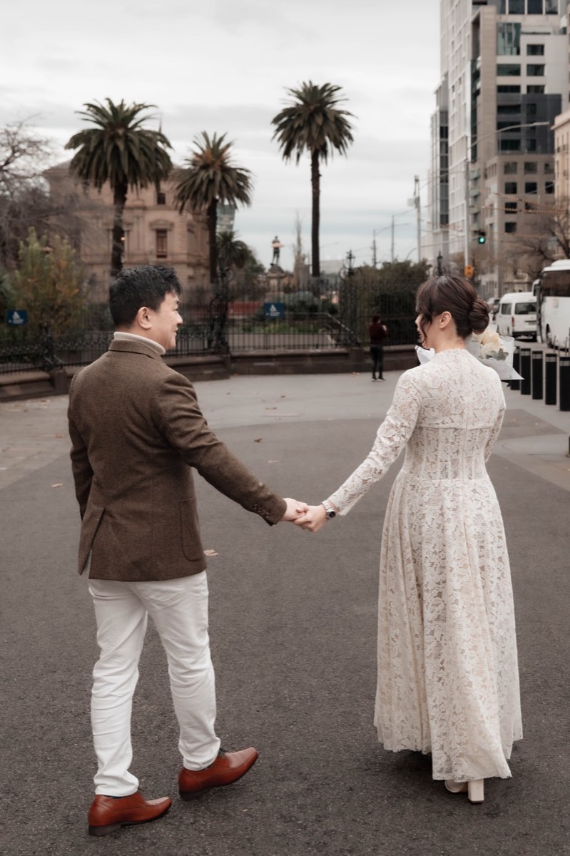 Holding hands at arm's length on a Melbourne street lined with palms