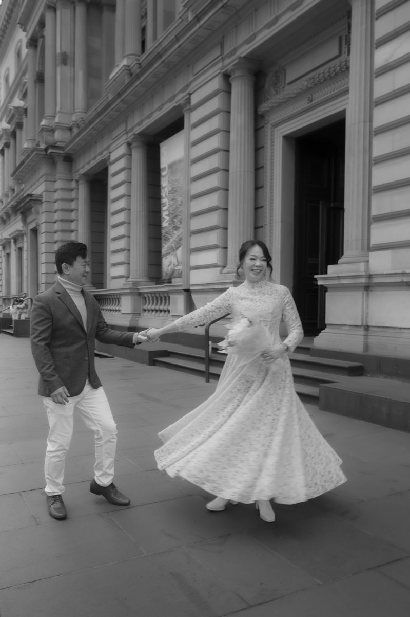 Black and white photograph of the bride spinning her dress outside the Old Treasury Building