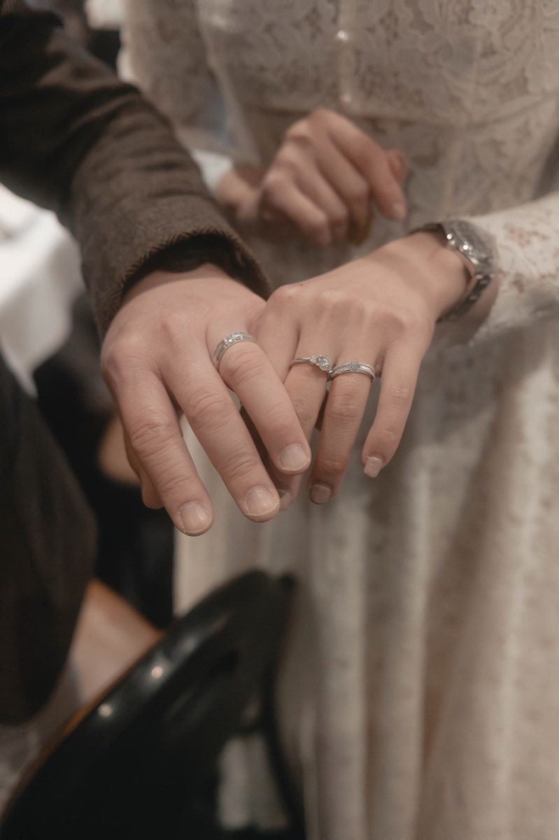 The couple's hands with new wedding rings, photographed at the dinner table